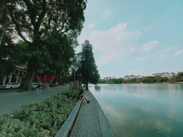 People relaxing by Hoan Kiem Lake, enjoying the peaceful scenery in Hanoi