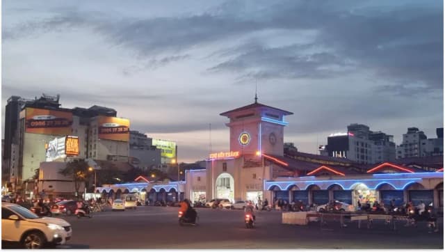 Cars and motorbikes passing by Ben Thanh Market at night