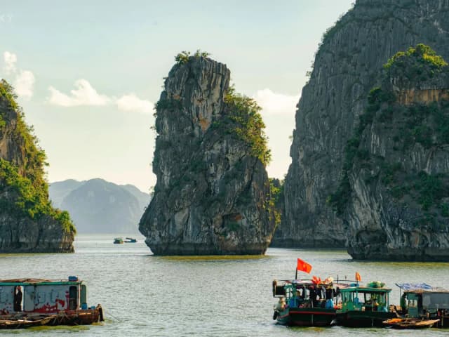 Boat sailing among limestone mountains in Ha Long Bay