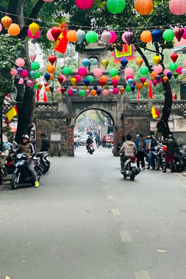 Bustling street life in Hanoi Old Quarter with motorbikes and local shops
