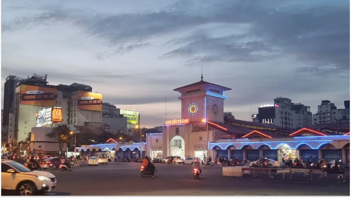 Cars and motorbikes passing by Ben Thanh Market at night