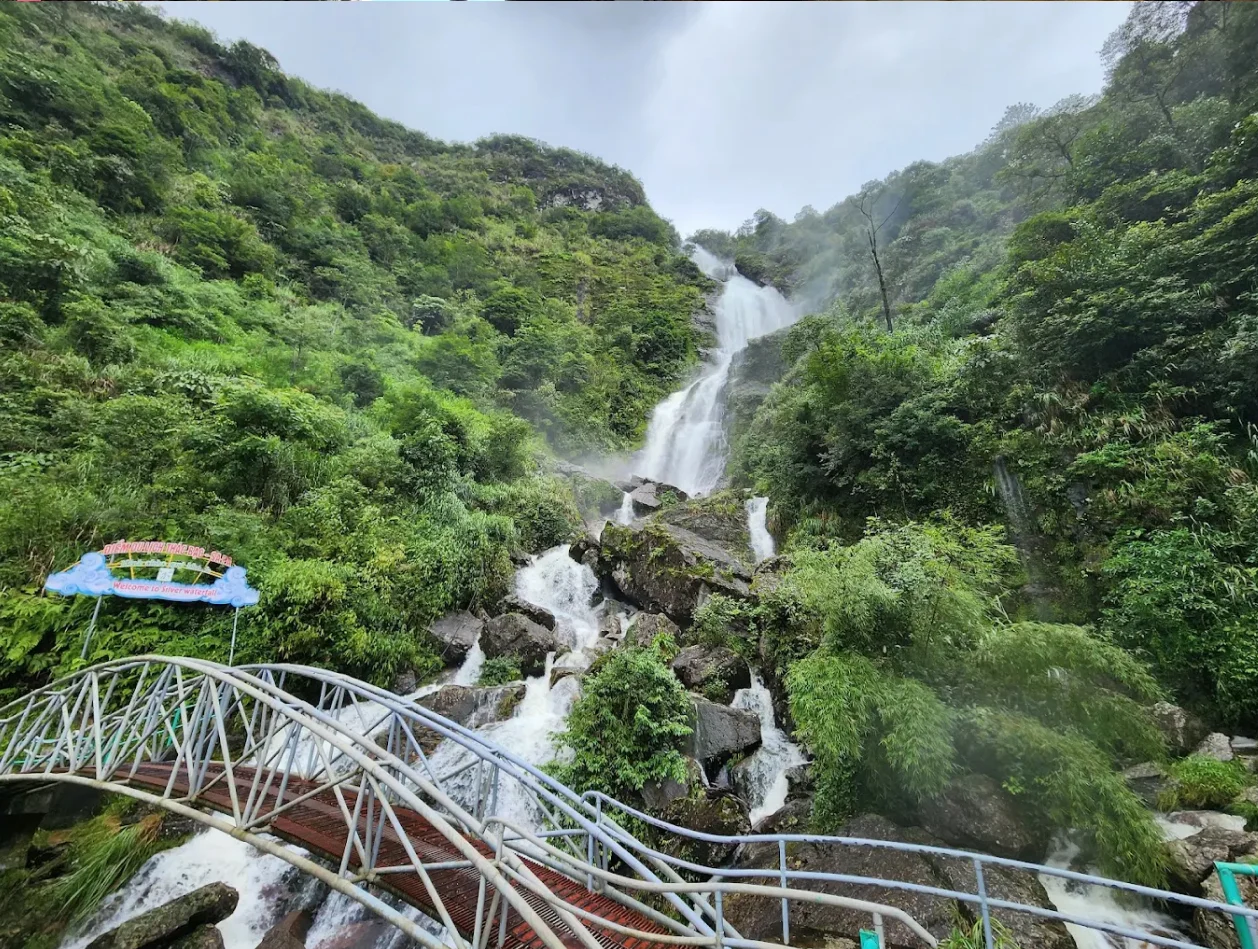 Thac Bac Waterfall cascading down lush green mountains